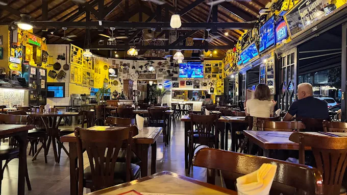 Interior aconchegante do Velho Rabo com mesas de madeira e iluminação calorosa